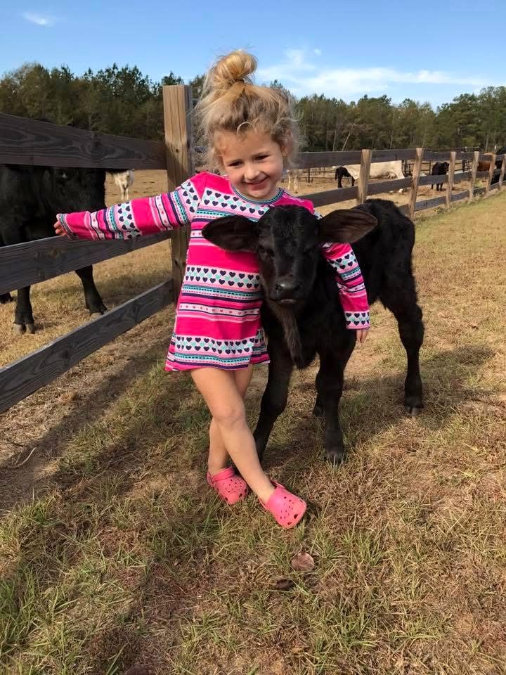 Ella as a little girl hugging a black bottle calf